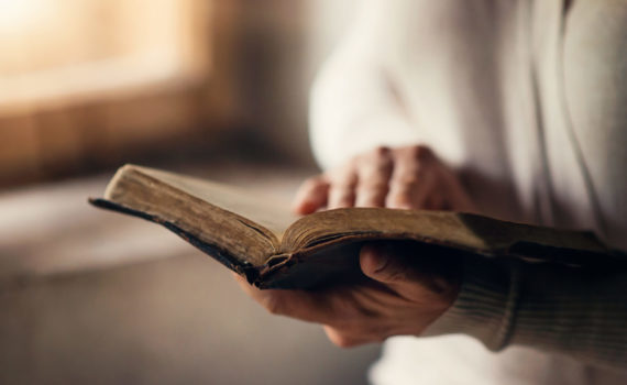 Unrecognizable woman holding a bible in her hands and praying